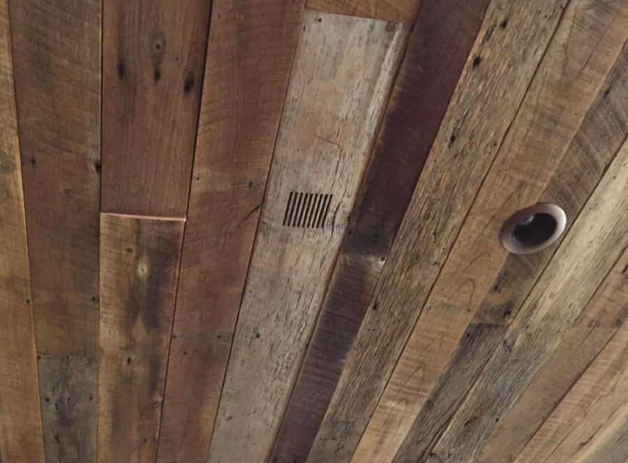 Slotted vent and recessed light fixture integrated into a rustic wood ceiling