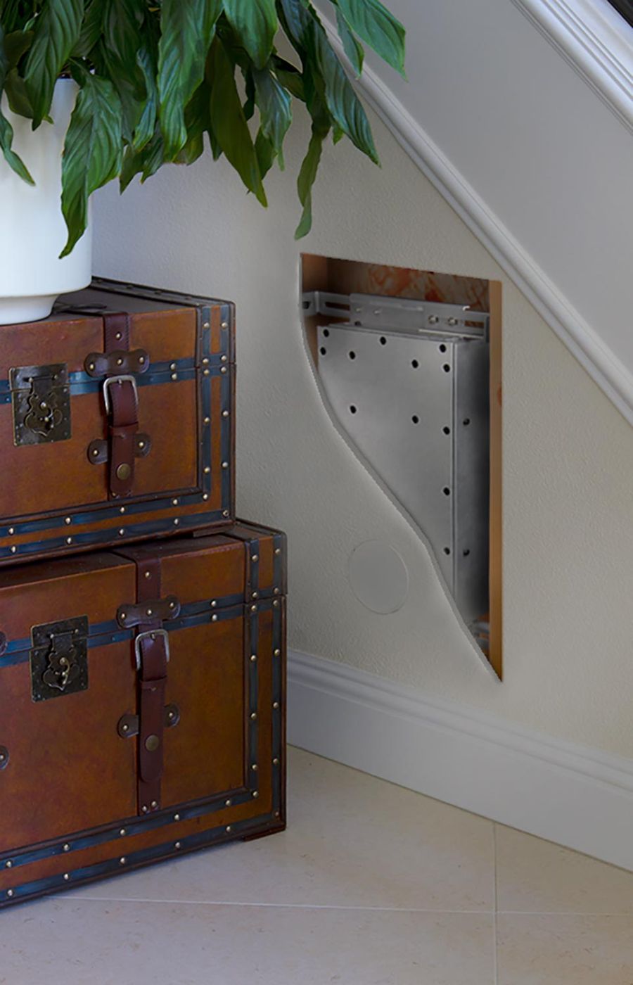 Cutaway view of a metal speaker housing installed behind a white wall