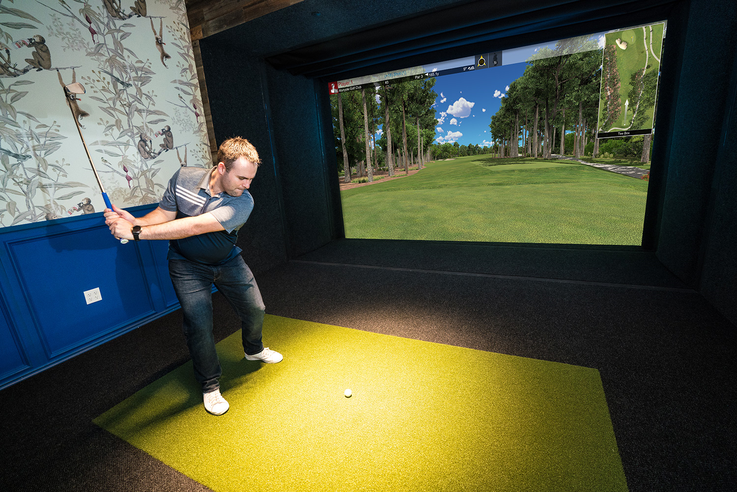 An indoor golf simulator with a projector and a realistic course display.