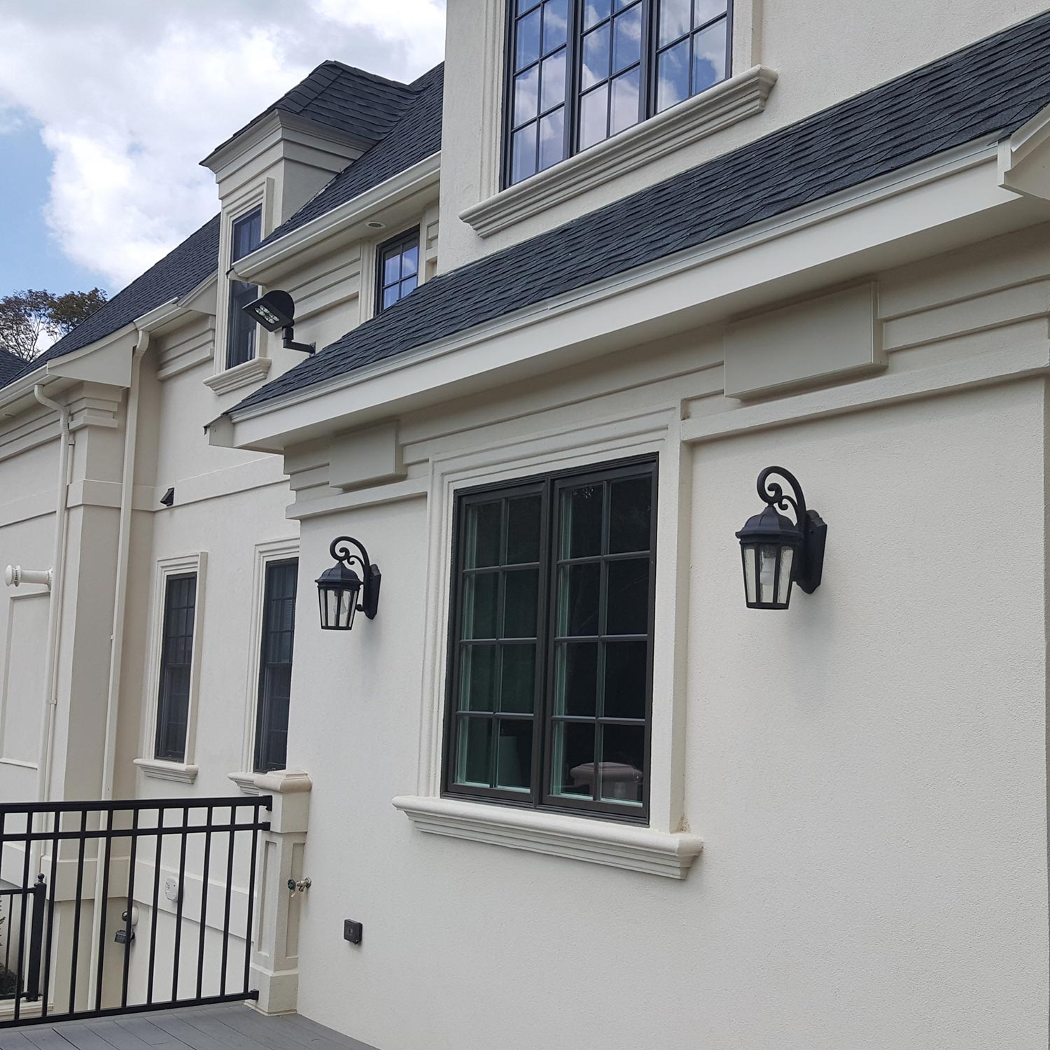 White stucco house exterior with black window frames and decorative wall lanterns